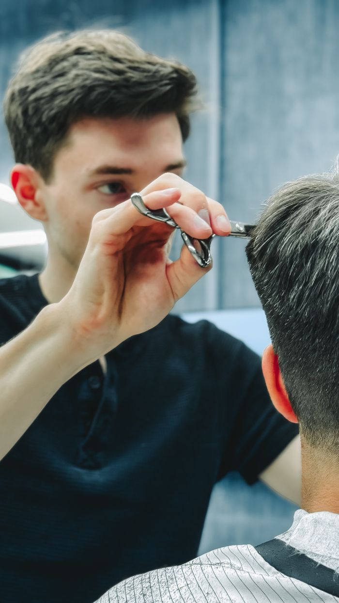 core-values Barber skillfully cutting a customer's hair in a contemporary barbershop setting.