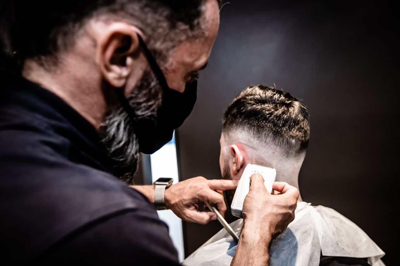 creative-approach-img Barber performing a detailed haircut, showcasing precision and skill in an indoor setting.